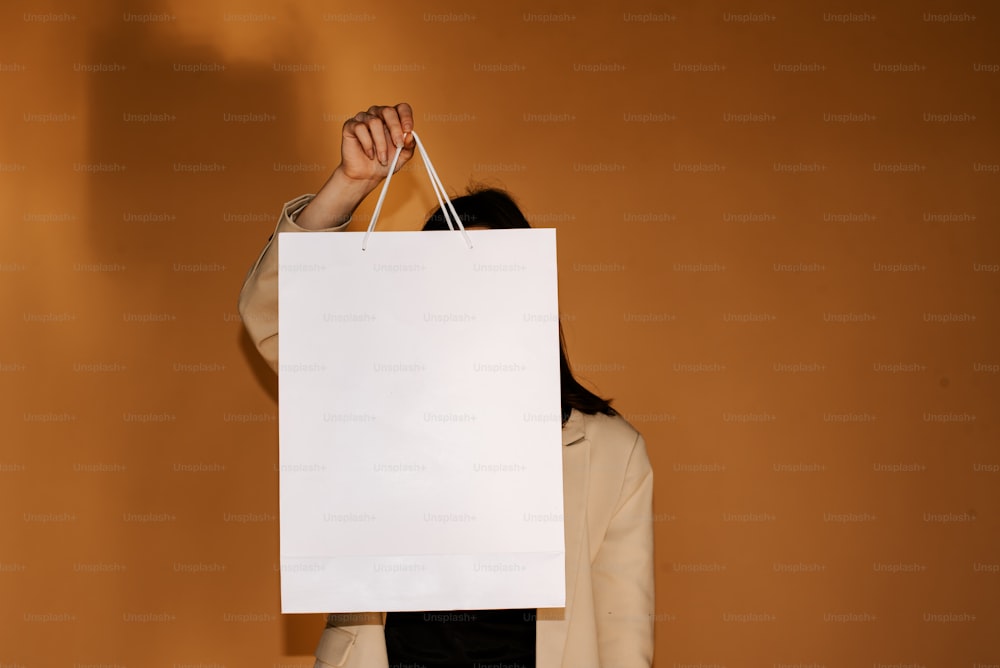 a woman holding a white shopping bag in front of her face