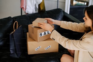 a woman sitting on a couch holding a box with a sale sign on it