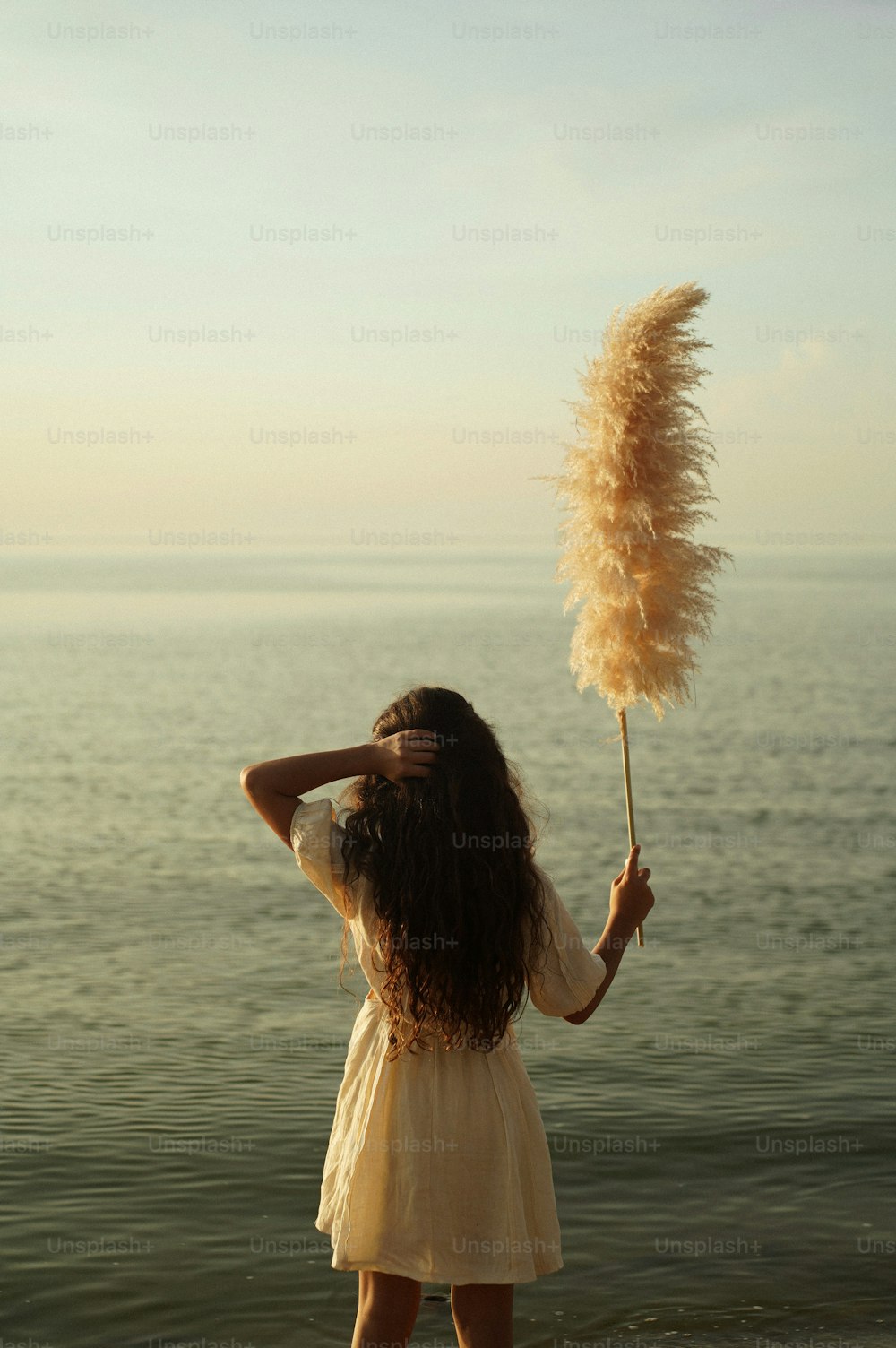 una donna in piedi su una spiaggia che tiene una bacchetta di piume