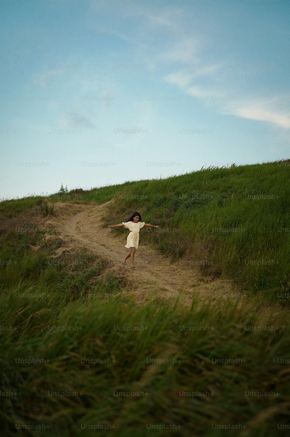 a young girl in a white dress standing on a dirt road