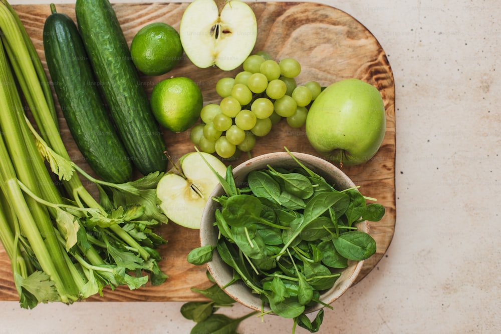 緑の野菜や果物をのせた木製のまな板