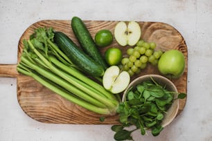 uma tábua de corte de madeira coberta com legumes verdes