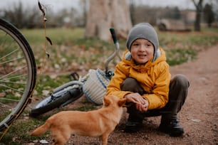 a young boy kneeling down next to a dog