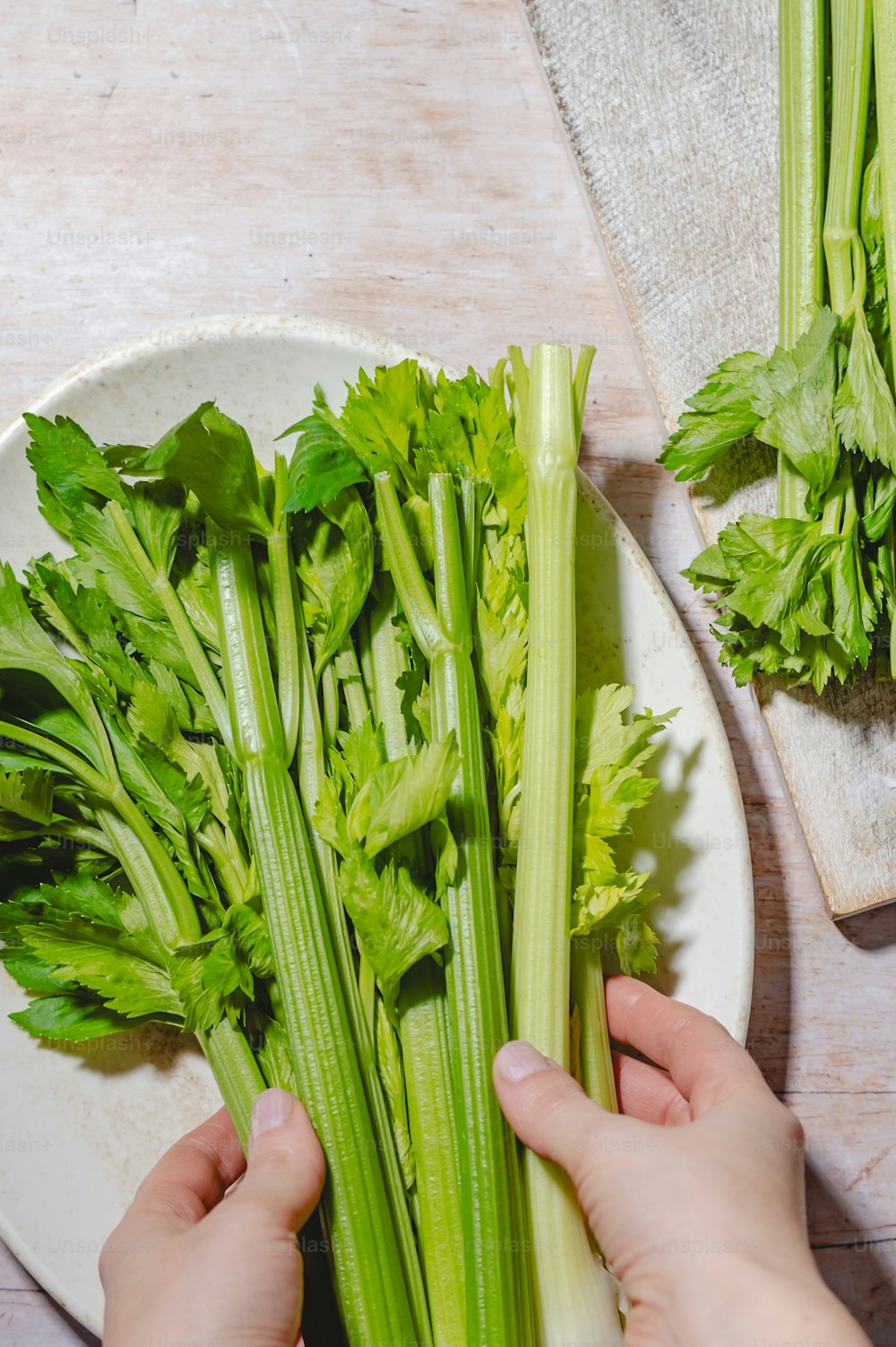 a person holding a bunch of celery on a plate