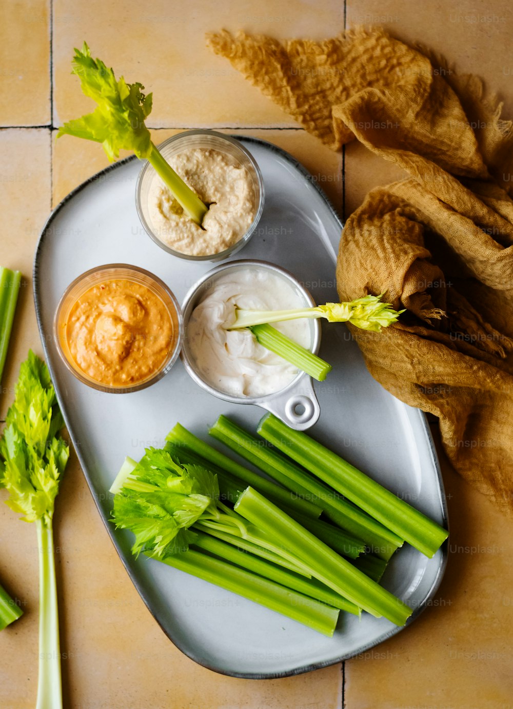 a plate with celery, dips, and bread on it