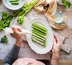 a person cutting celery on a white plate