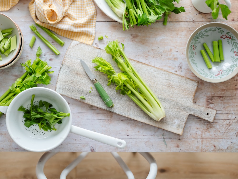 a cutting board topped with celery next to a bowl of celery