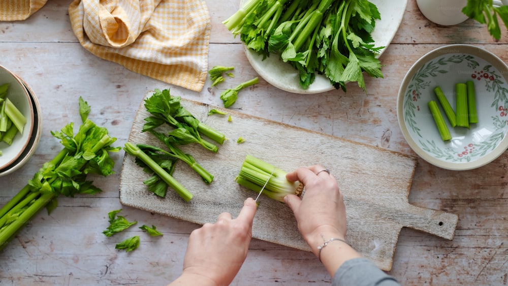 a person chopping celery on a cutting board