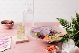 einen Tisch mit einer Schüssel Gemüse und einem Glas Wasser
