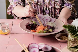 a woman holding chopsticks over a bowl of food