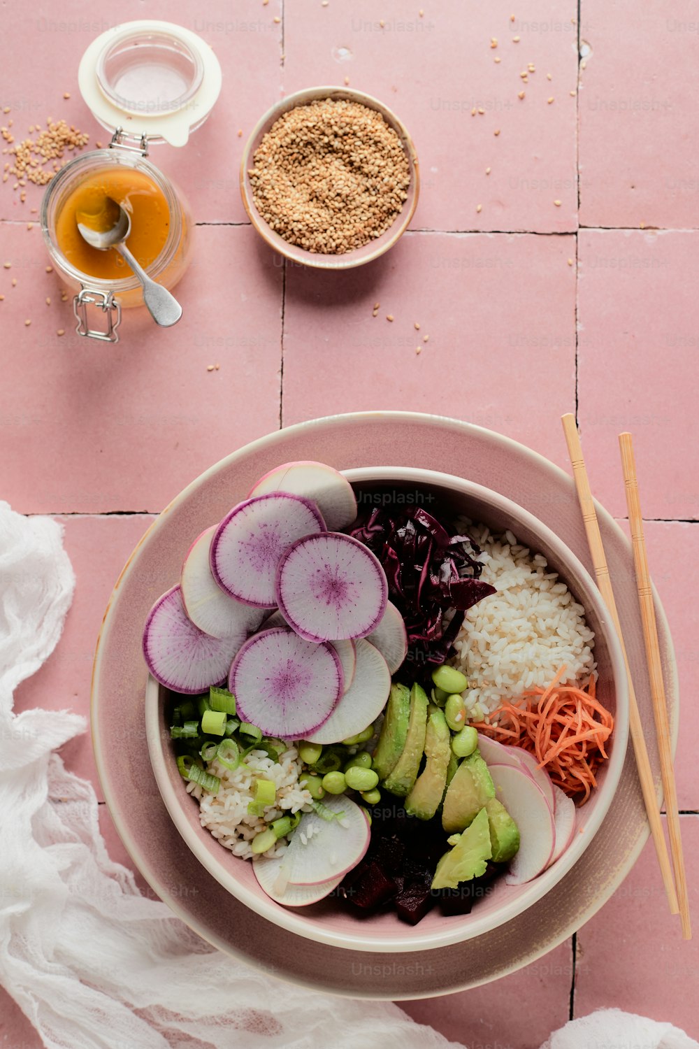 a bowl of food on a pink table with chopsticks