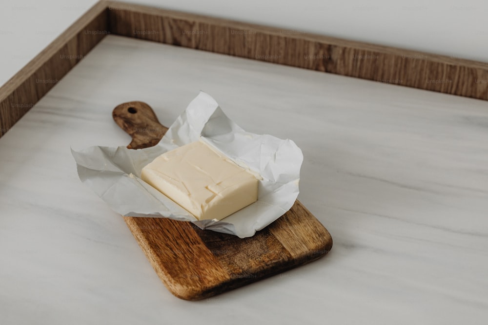 a piece of butter sitting on top of a wooden cutting board