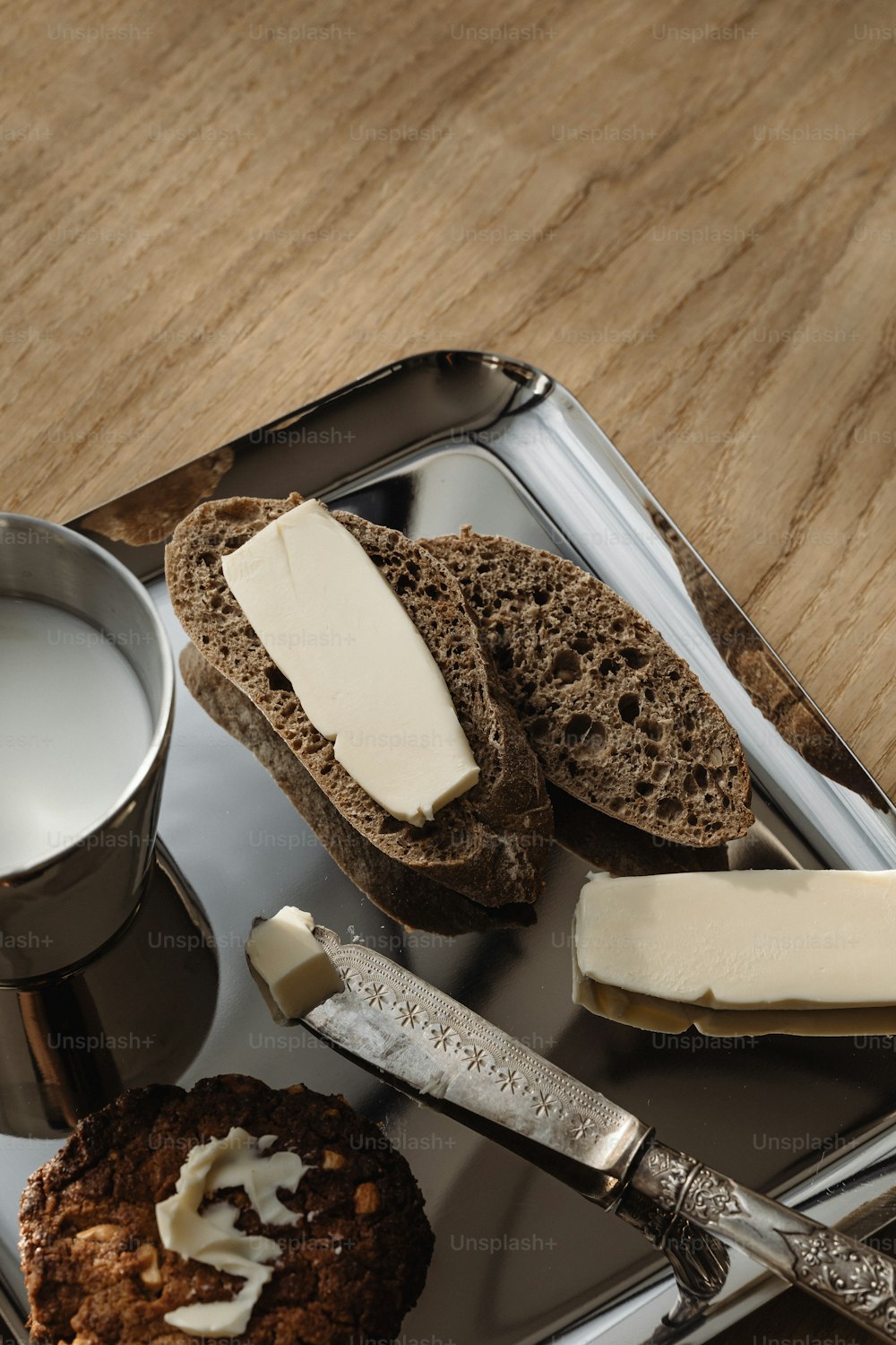 a tray with bread, butter, and a cup of milk