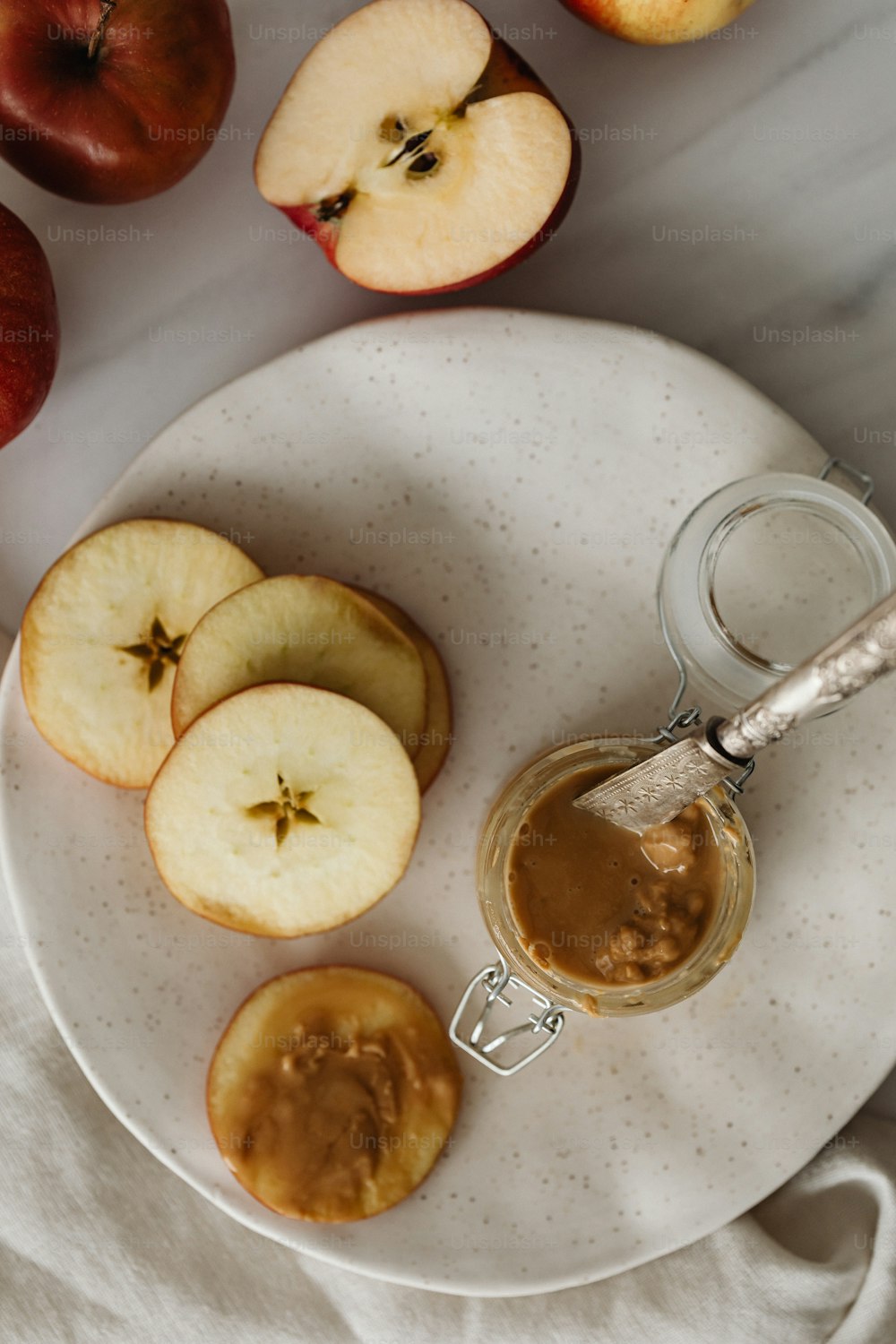 a white plate topped with apples and a jar of peanut butter