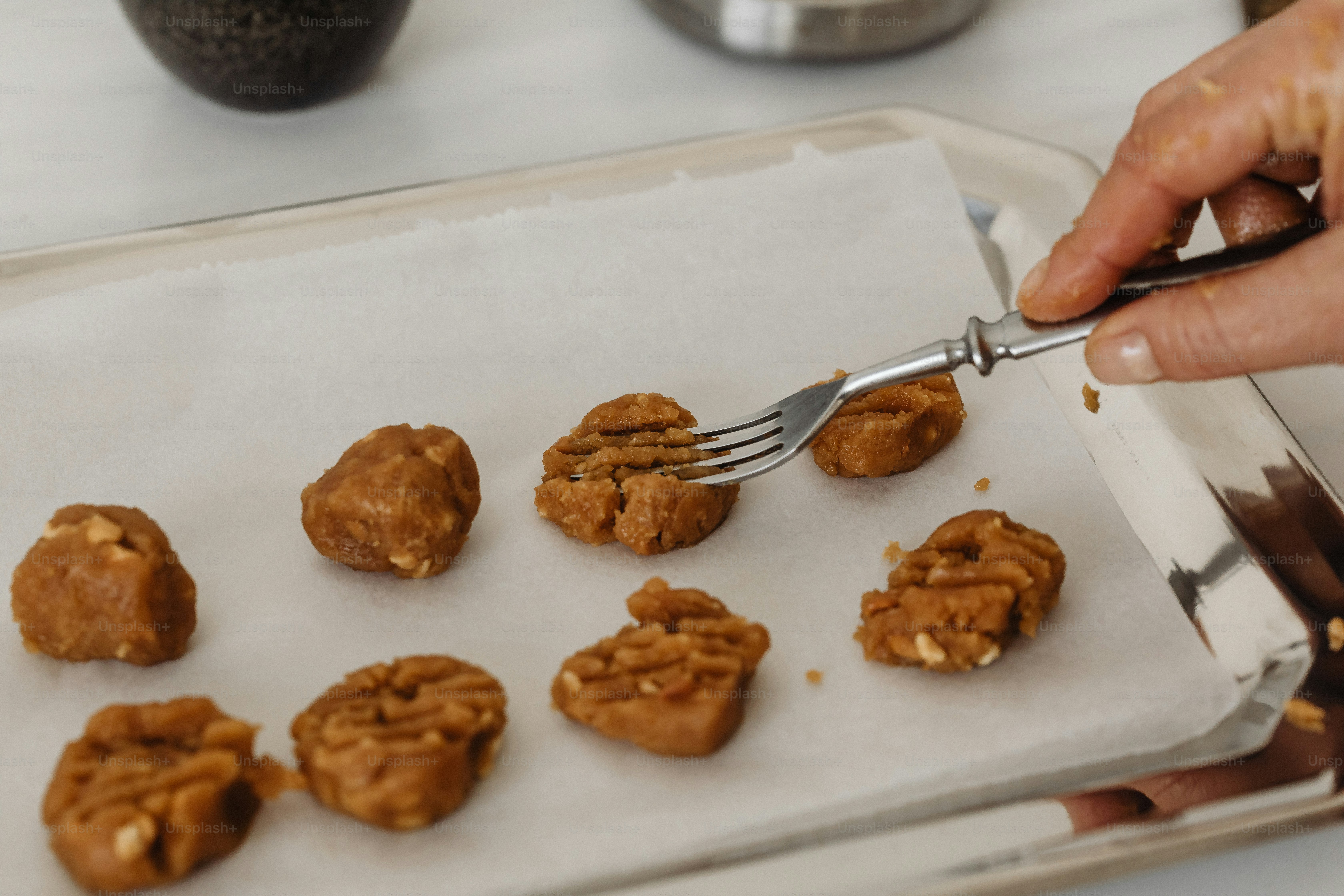 a person holding a fork over a tray of cookies