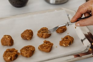 a person holding a fork over a tray of cookies