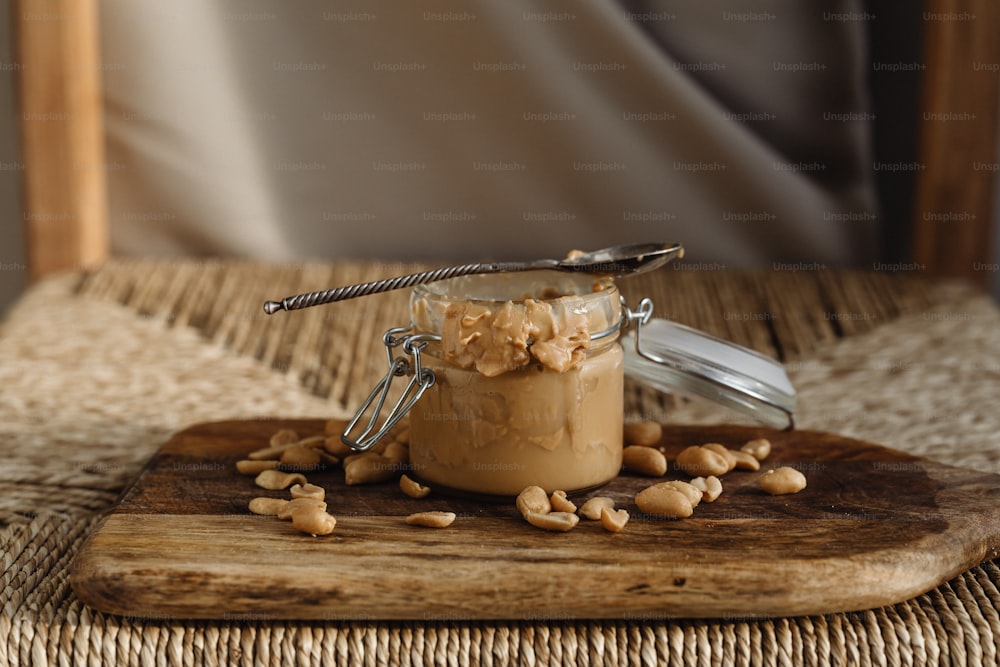 un pot de beurre de cacahuète sur une planche à découper en bois