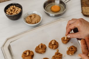a person putting peanut butter on cookies on a tray