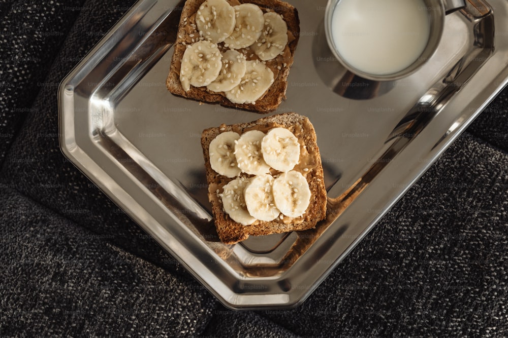 two pieces of toast with banana slices and a glass of milk