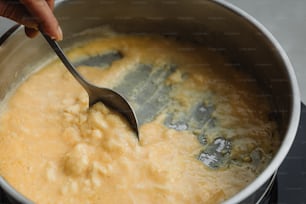 a person stirring a pot of food with a spoon