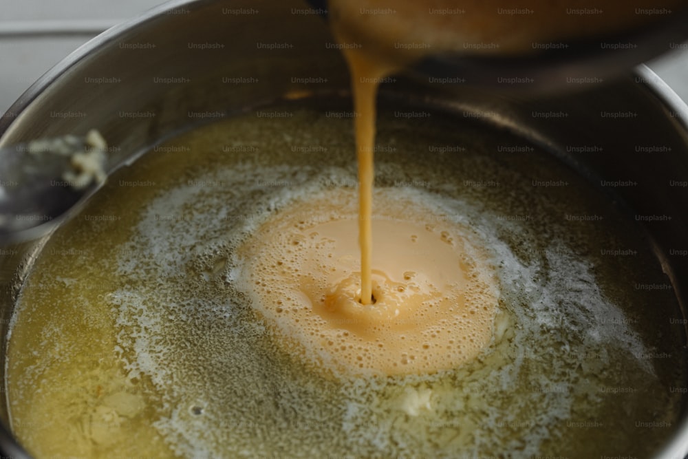 a sauce being poured into a pot of food