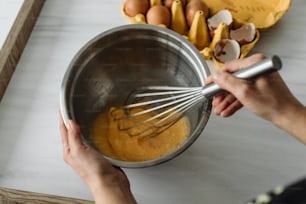 a person mixing batter in a metal bowl
