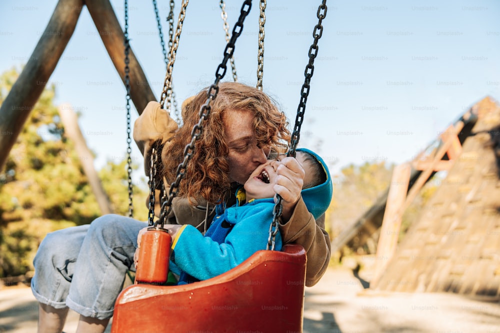 a woman sitting on a swing with a child