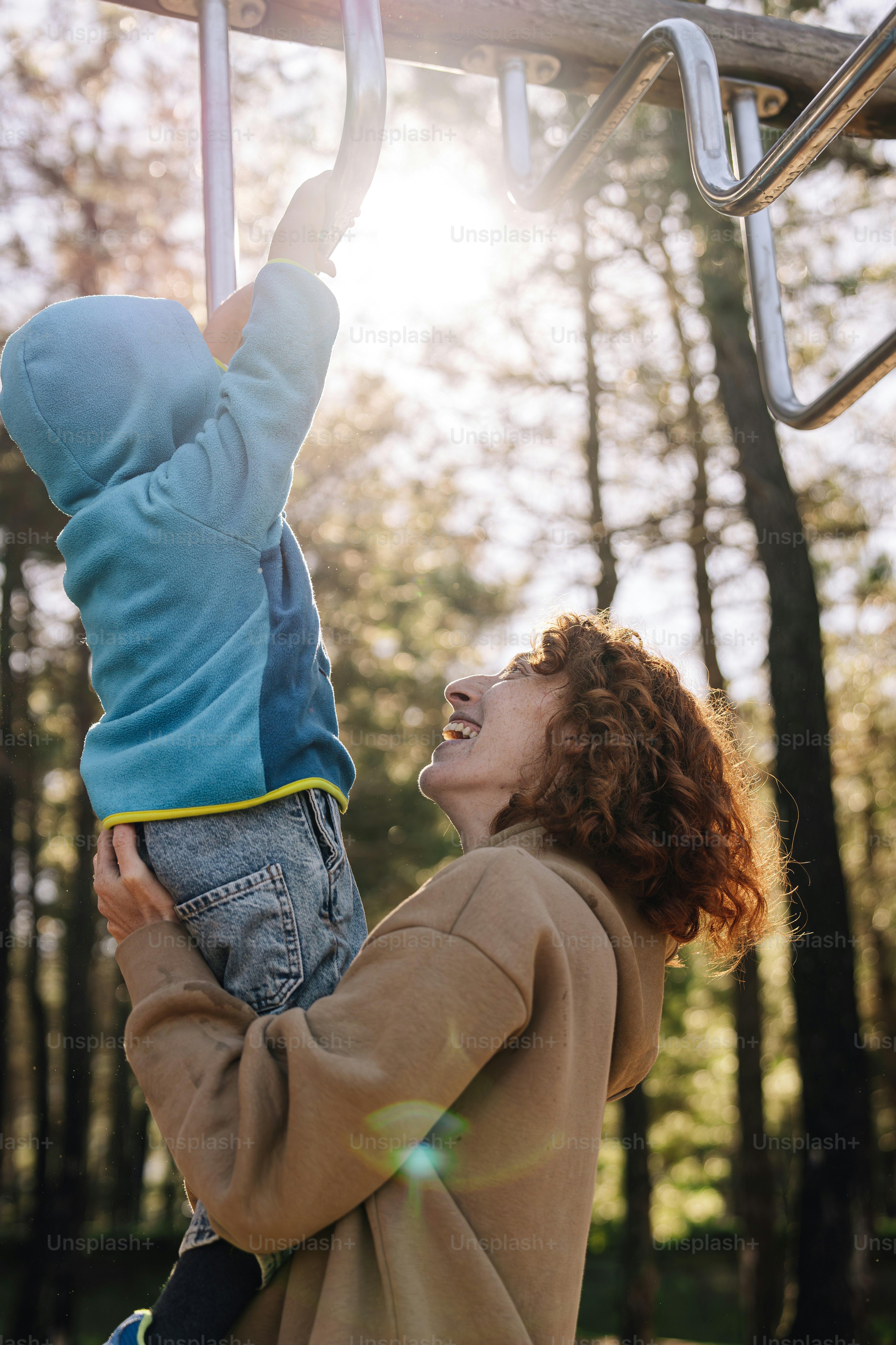 a woman holding a child up to a metal bar