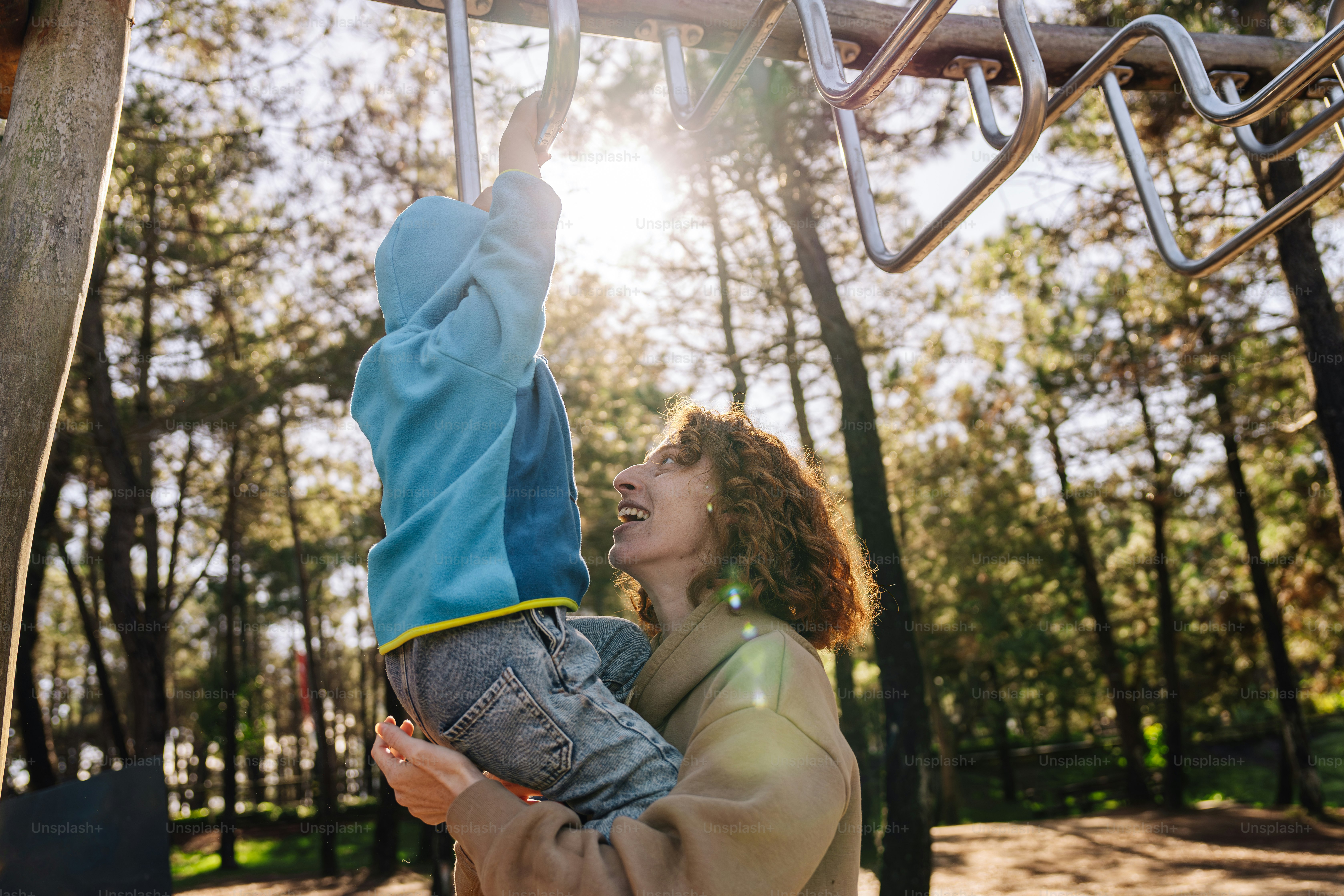 a woman holding a child up to a metal structure
