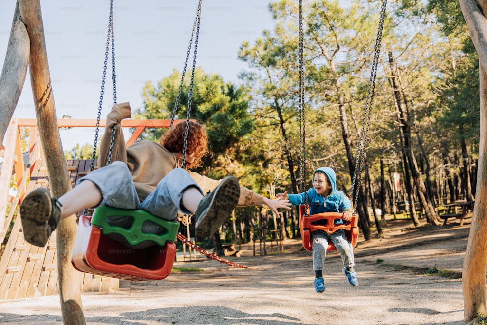 two children playing on swings in a park