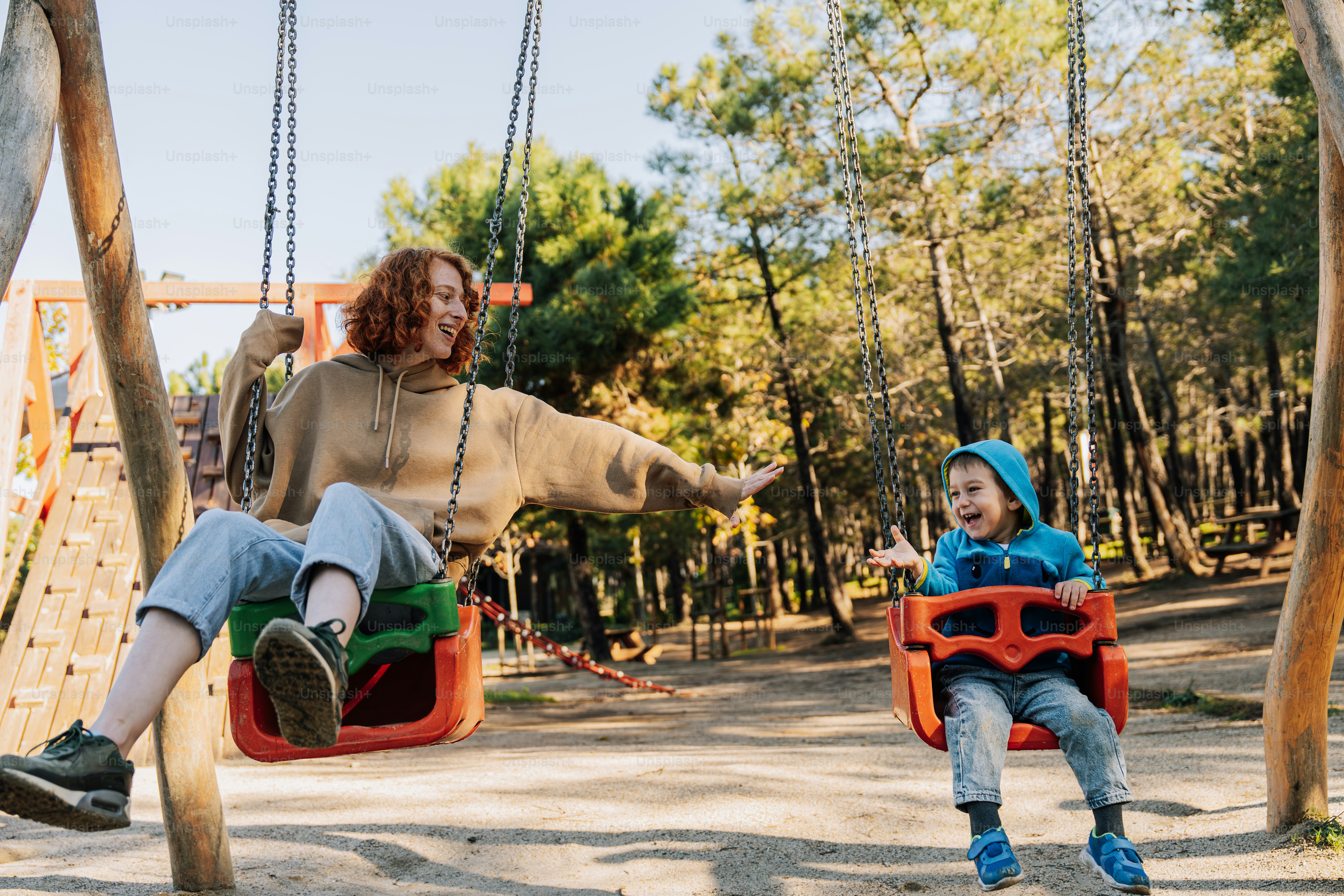 a woman sitting on a swing next to a child