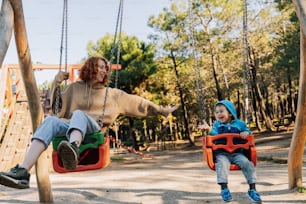 a woman sitting on a swing next to a child