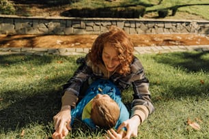 a woman is playing with a child in the grass