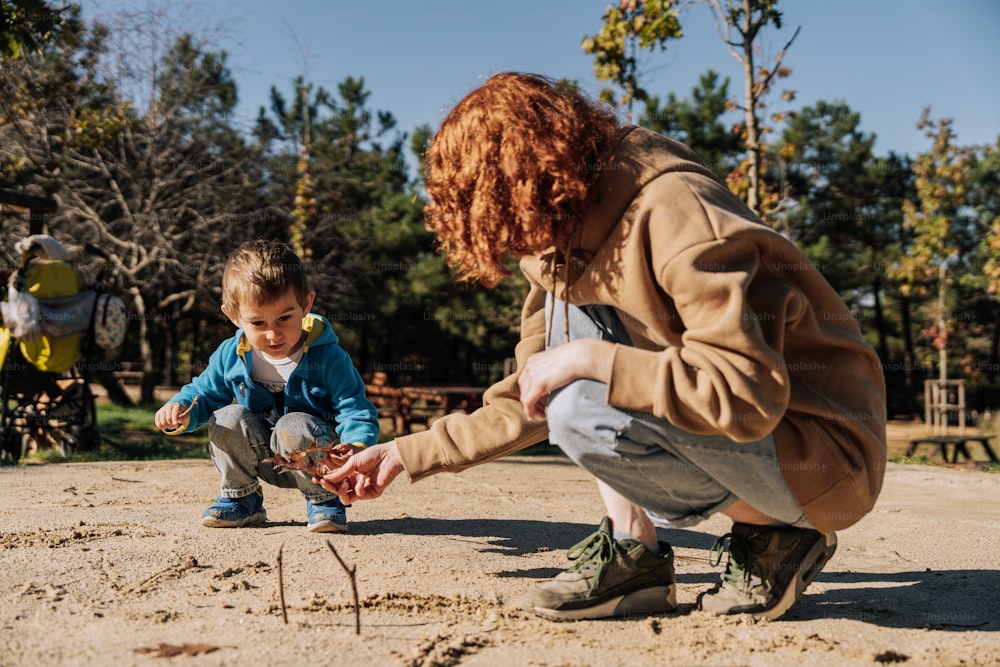 a woman kneeling down next to a little boy