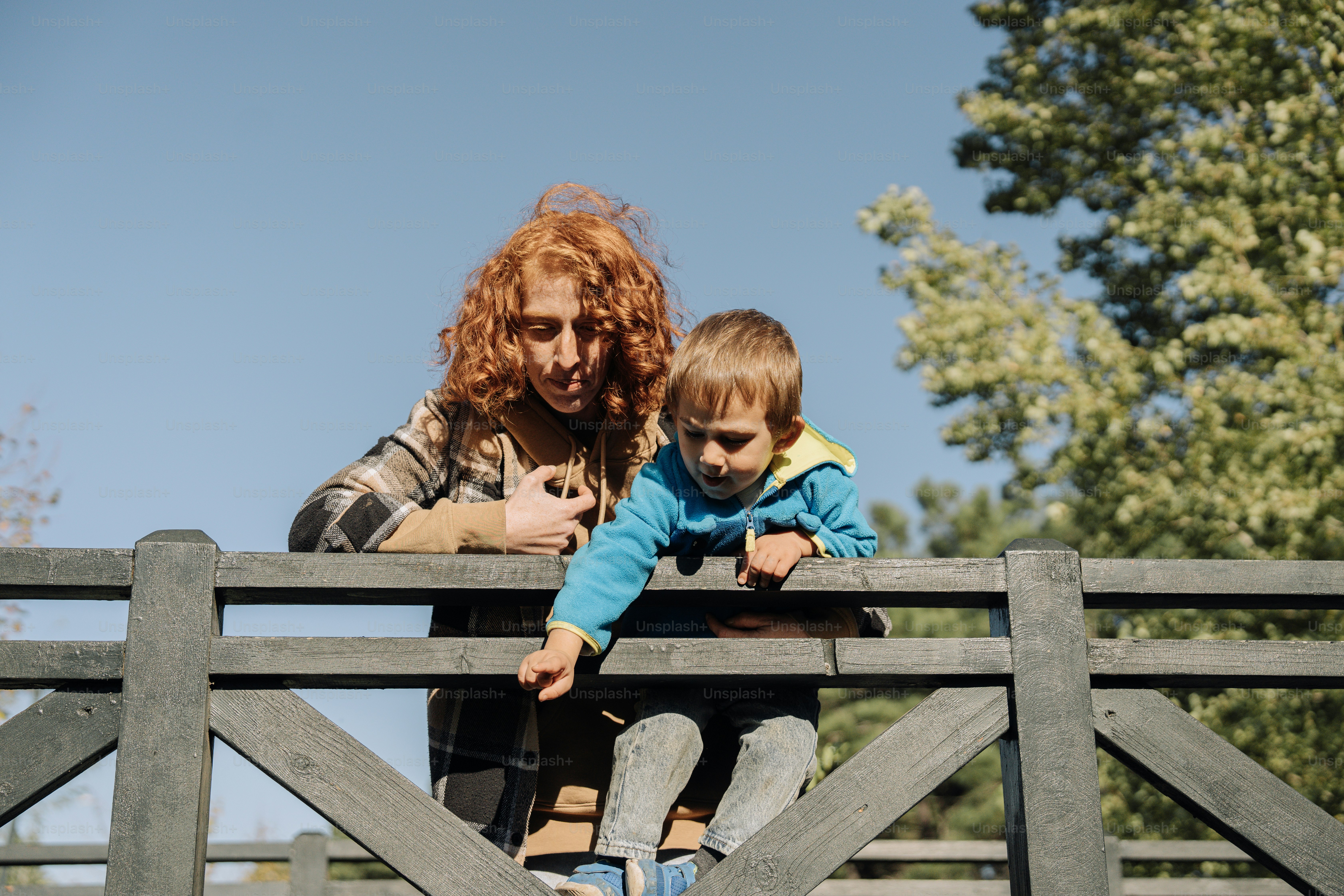 eine Frau, die ein Kind auf einer Holzbrücke hält