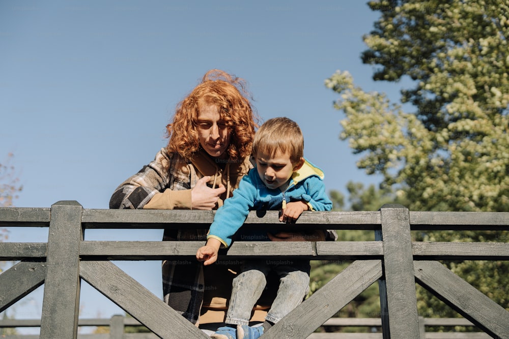 a woman holding a child on top of a wooden bridge