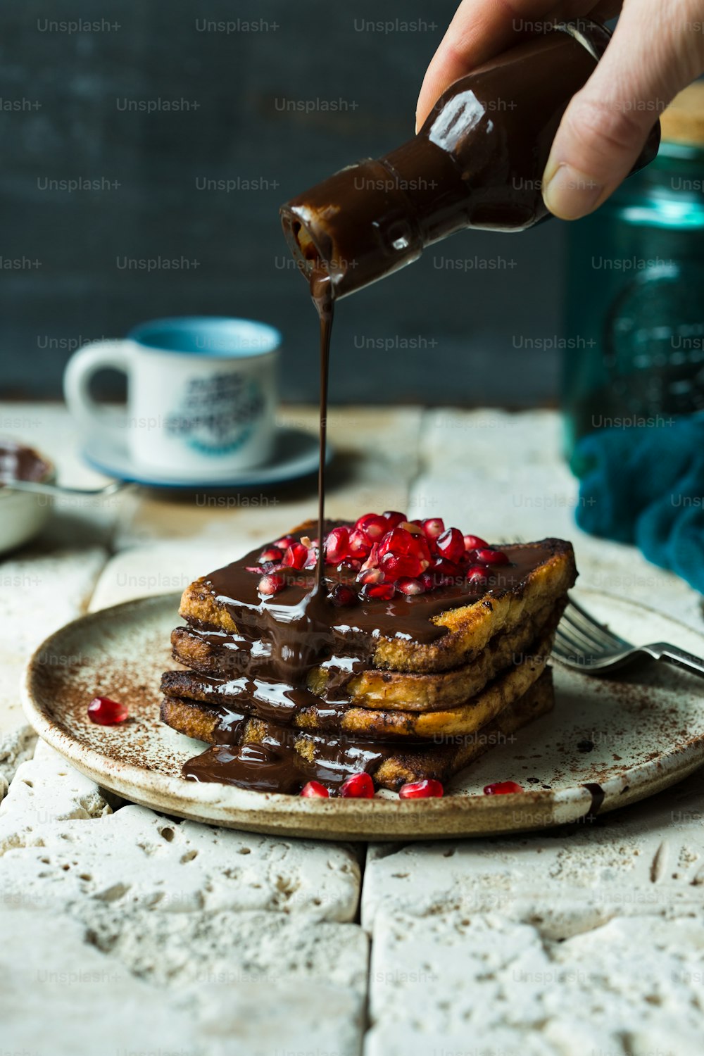 a person drizzling chocolate onto a stack of pancakes