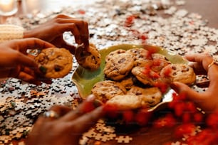 um grupo de pessoas juntando biscoitos em um prato