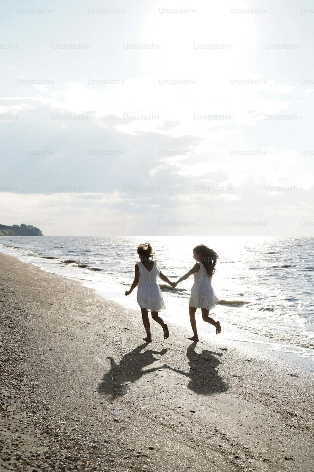 손을 잡고 해��변을 달리는 두 어린 소녀