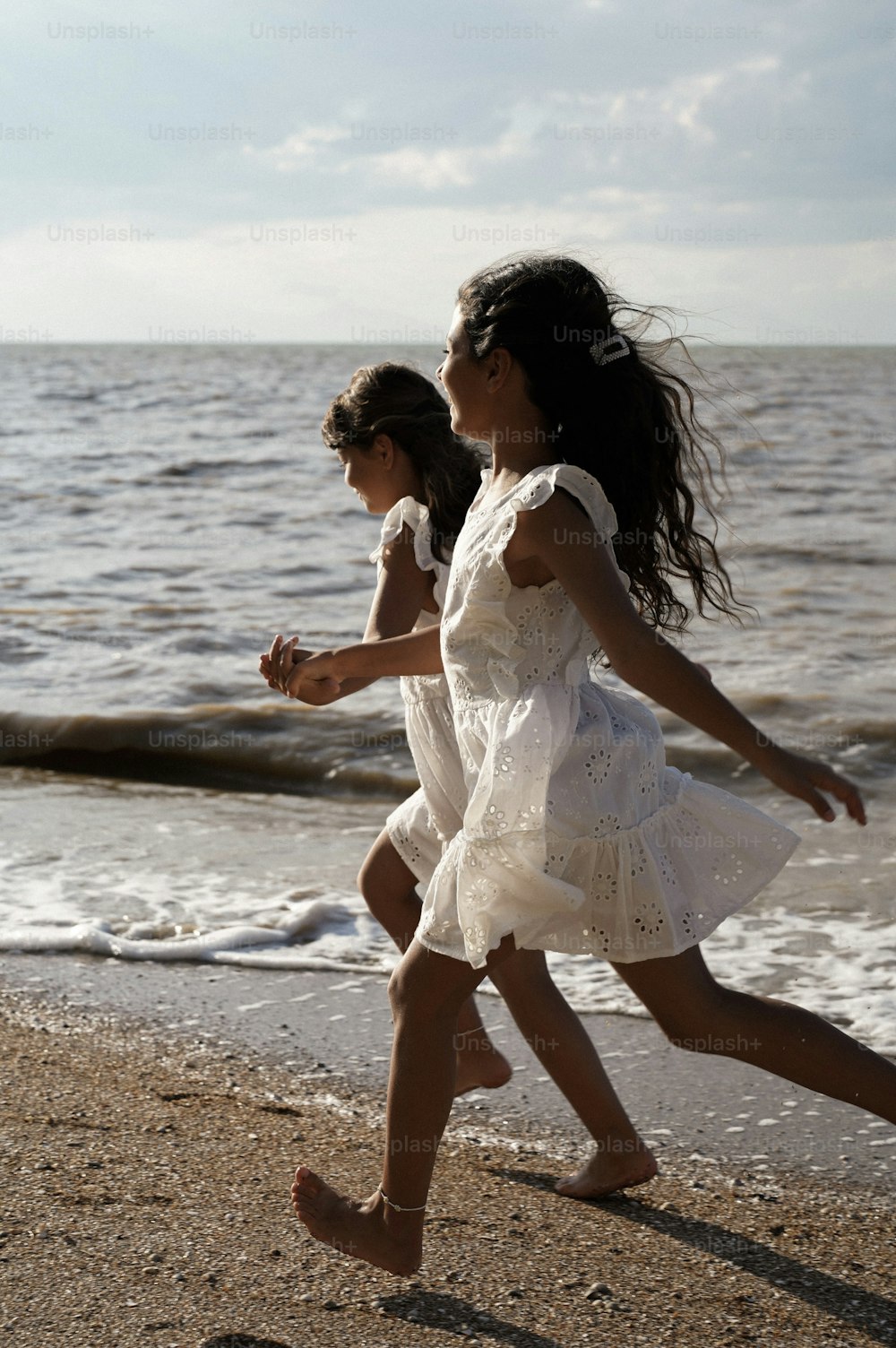two little girls running on the beach near the water