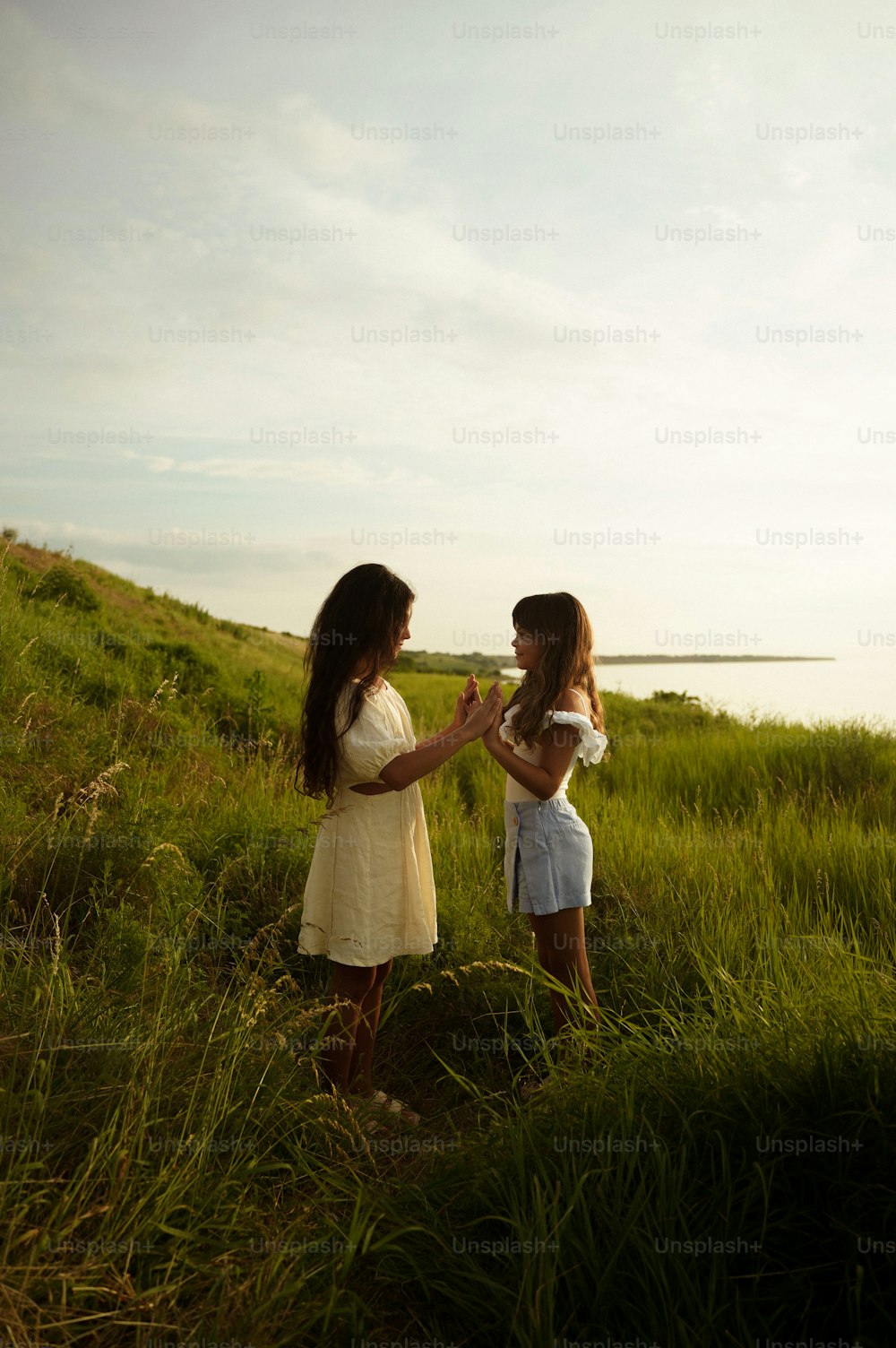 Dos mujeres de pie en un campo tocándose las manos