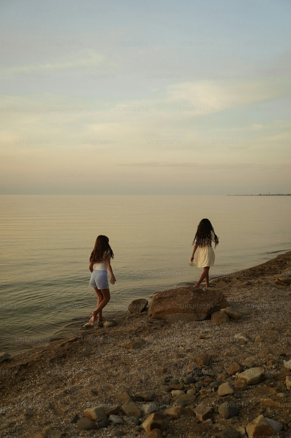 두 어린 소녀가 물가를 따라 걷고 있습니다.