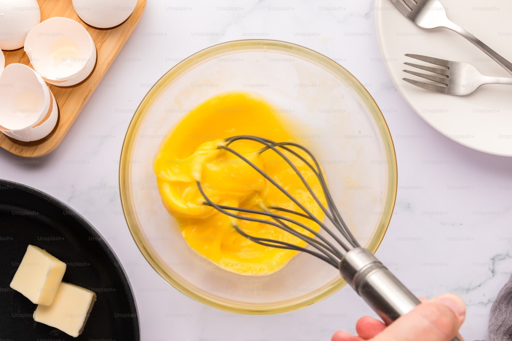 a person whisking eggs in a bowl with a whisk