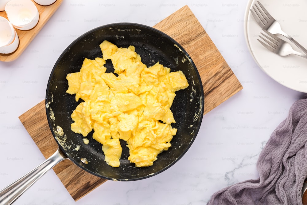scrambled eggs in a frying pan on a cutting board