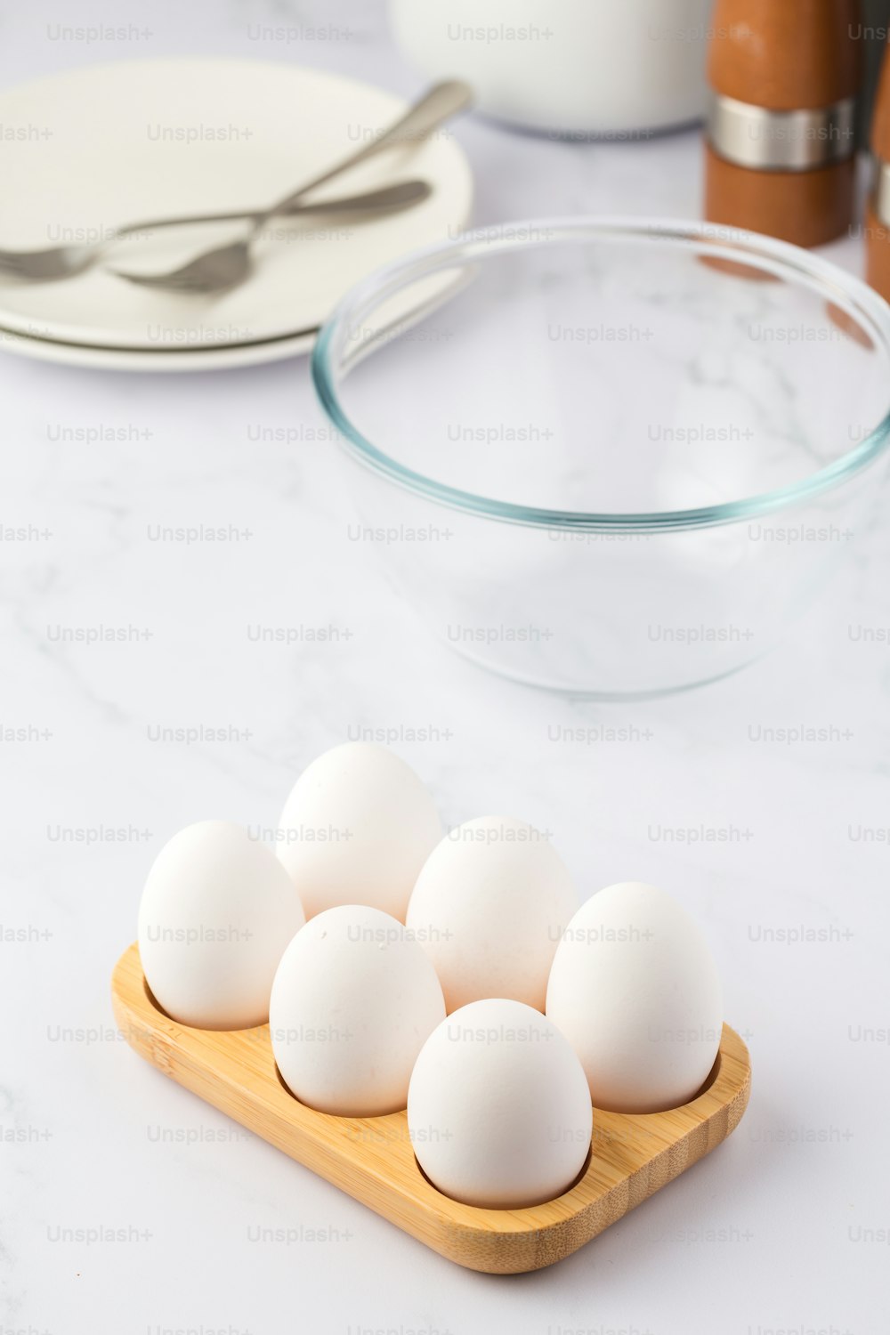 una tabla de madera cubierta con huevos blancos junto a un cuenco de huevos
