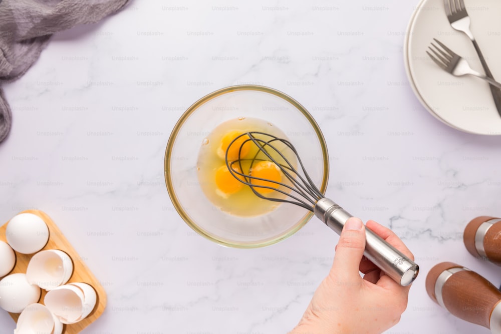 a person whisking eggs in a glass bowl