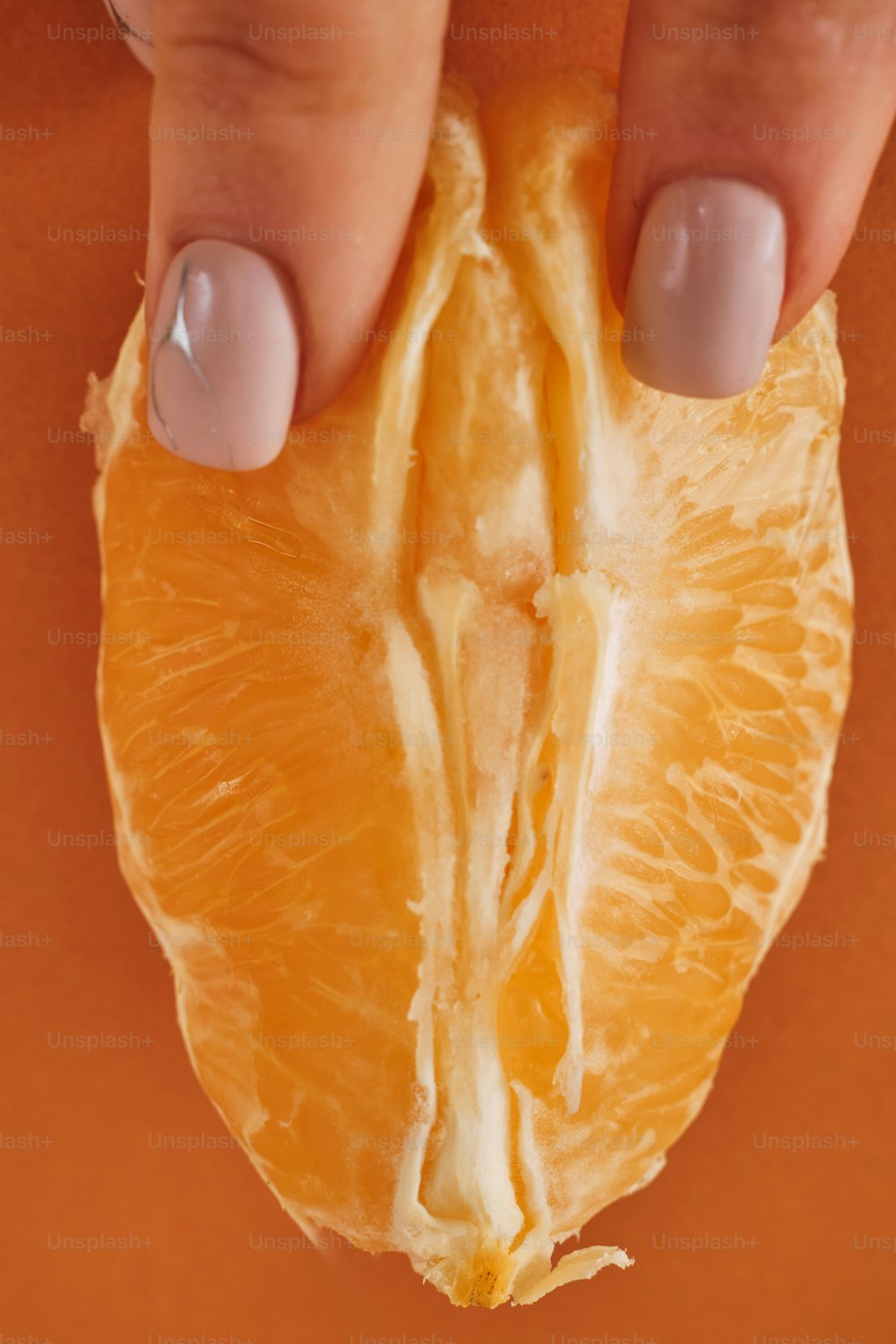 die Hand einer Frau, die eine halbe Orange hält