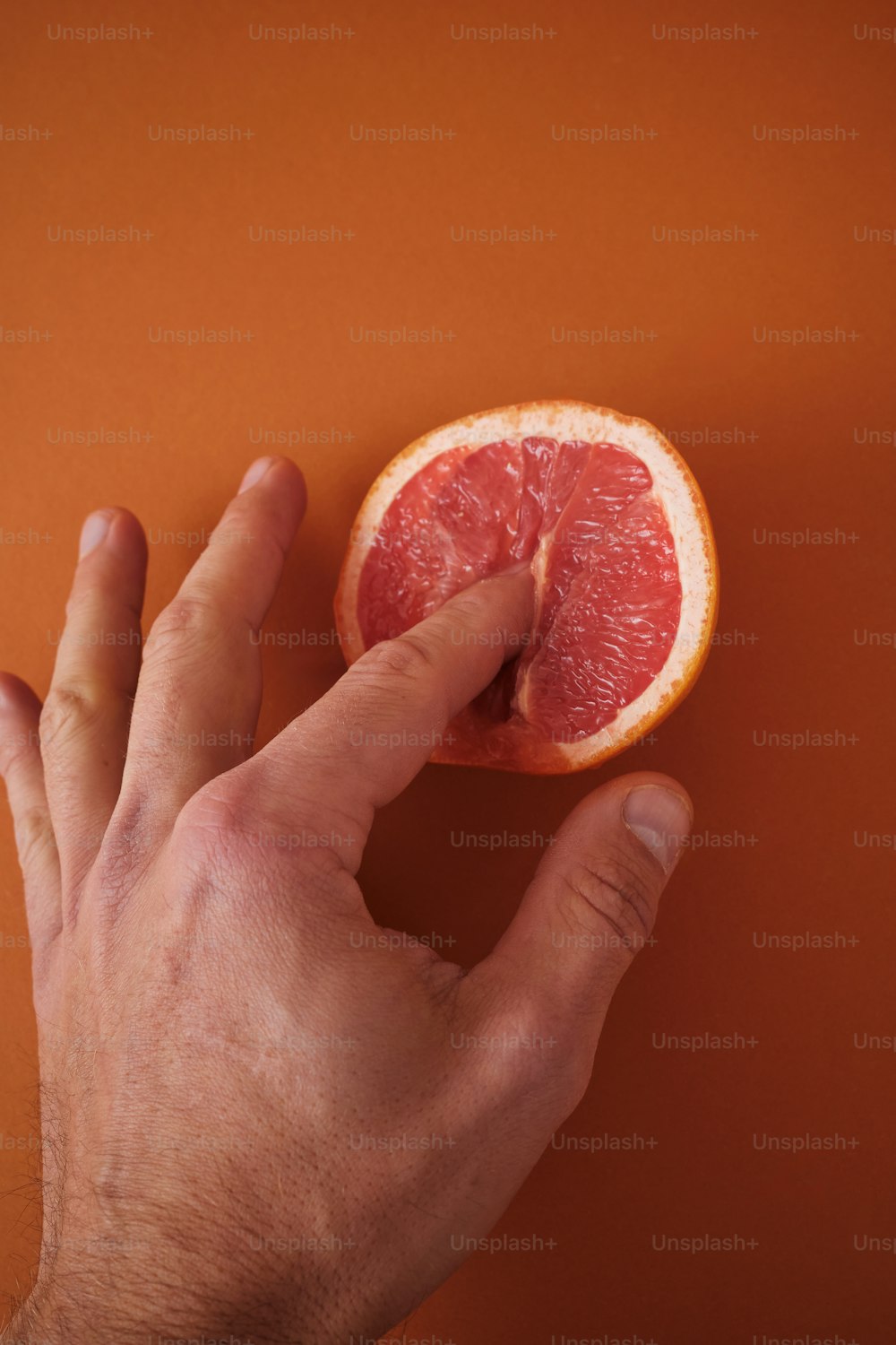 a hand reaching for a grapefruit on an orange