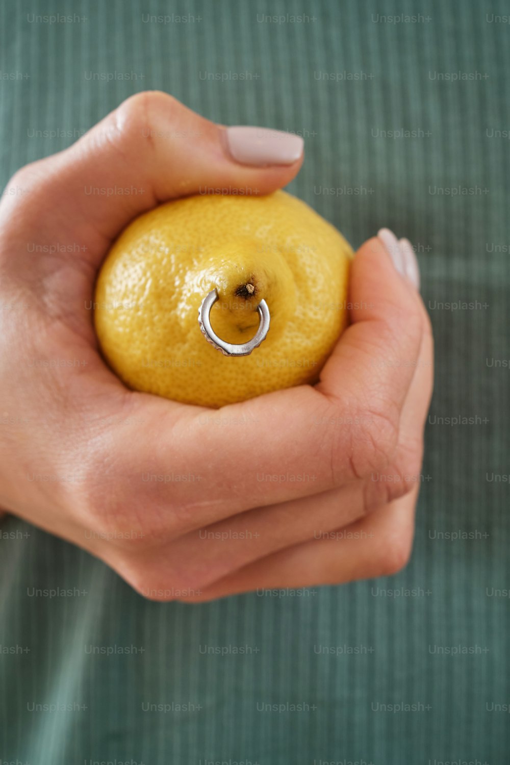 eine Person, die eine Zitrone mit einem Ring daran hält