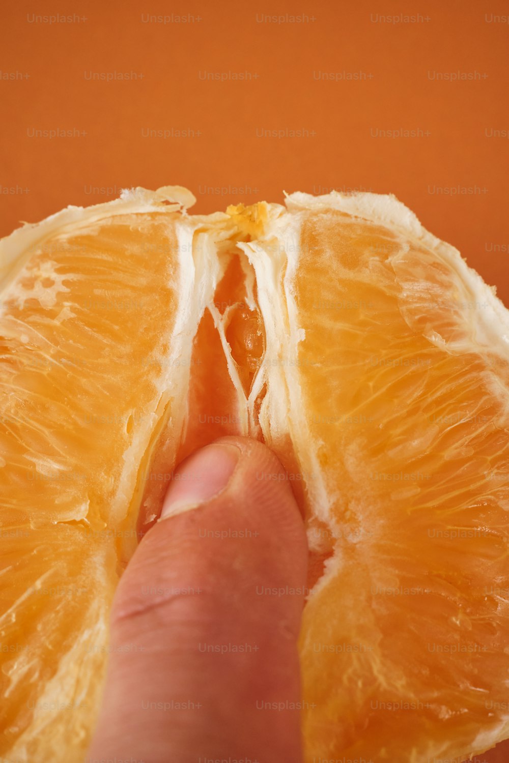 a hand is holding an orange that has been cut in half